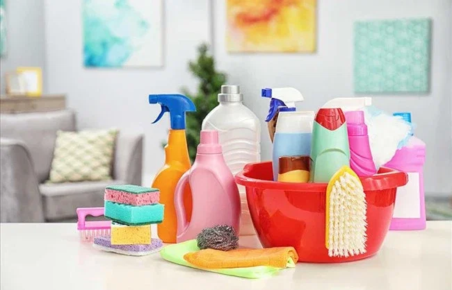 Household cleaning products, sprays and brushes arranged on a table