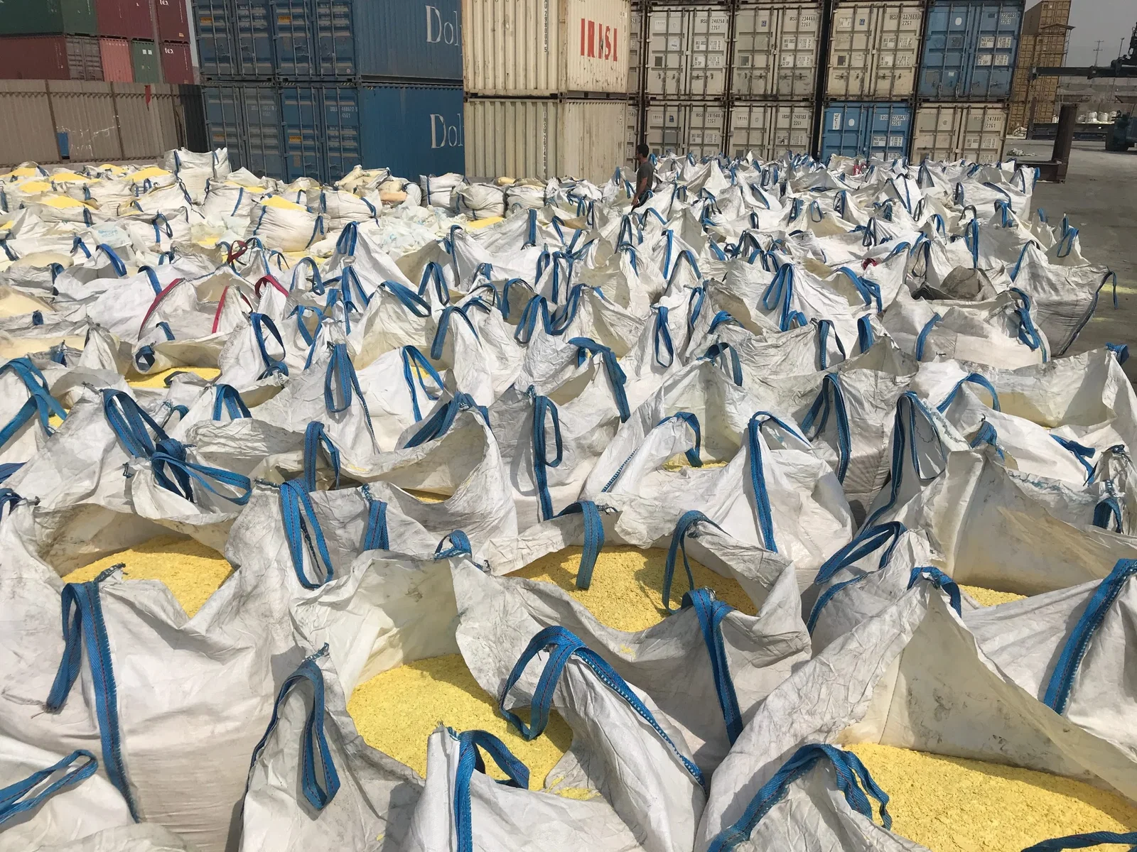 Bagged sulfur staged at a container terminal — the last handling step before the material becomes somebody's input