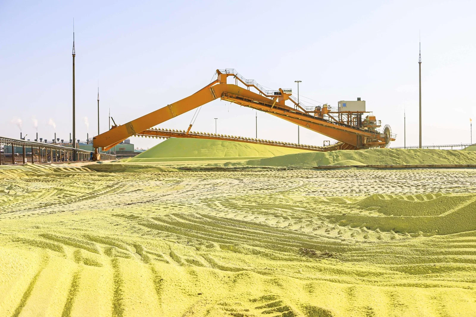 Bucket-wheel stacker forming a sulfur block at a gas processing plant storage yard