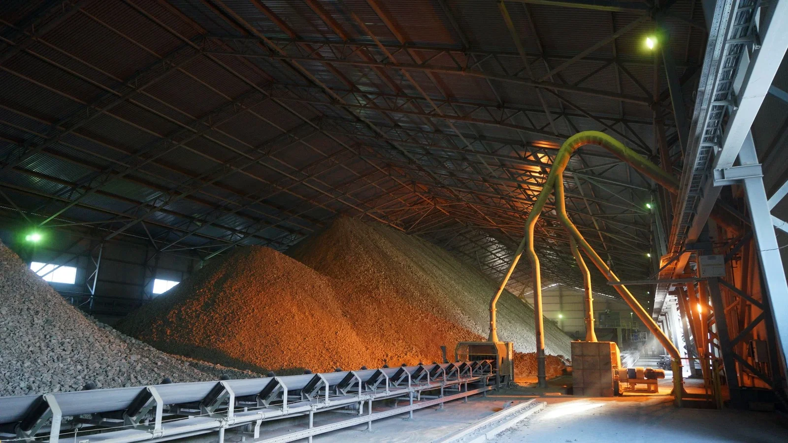 Kireçtaşı ve düzeltici malzemenin katmanlı yığınlarını besleyen stacker bomu ve bantlı konveyörüyle kapalı ön harmanlama stok sahası