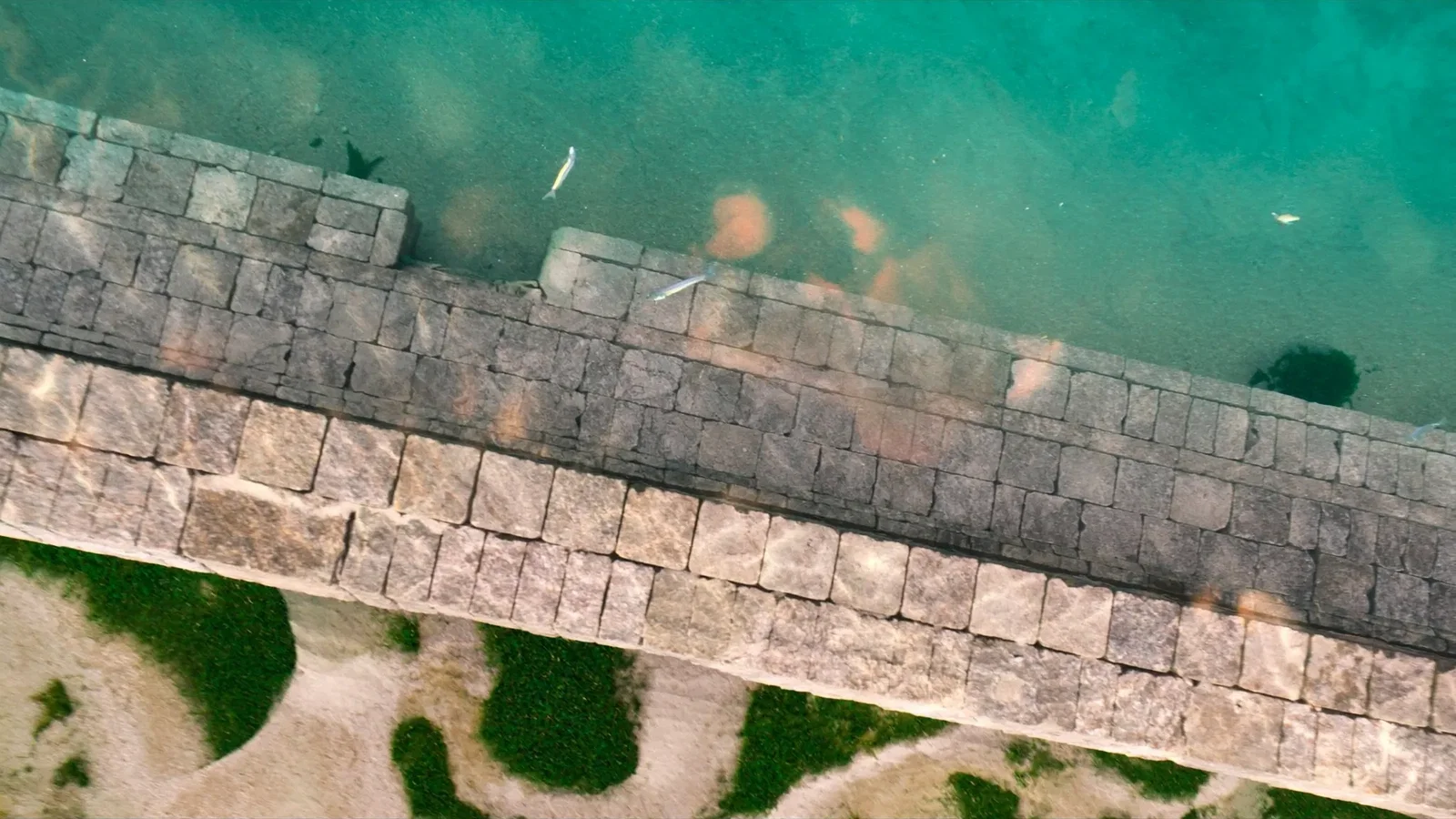 Overhead view of the submerged block courses of an ancient harbour wall under clear turquoise water at Gumusluk